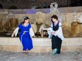 Two girls - members of the club of knights of Jerusalem, dressed in traditional costumes of medieval ladies, sit at night near the