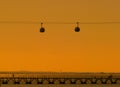 Telecabines cable cars at sunrise and people walking by the Tagus river at Park of Nations Parque das Nacoes, in Lisbon,