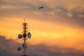 Telecom Signal Tower in sunset and plane is flying through. Royalty Free Stock Photo