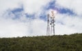 Telecommunication mast TV antennas wireless technology on a hilltop of green mountain, blue sky and cloud in background Royalty Free Stock Photo