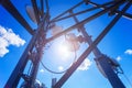 Telecommunication tower with microwave, radio antennas and satellite dishes with shadows on the roof against blue sky and sun. Royalty Free Stock Photo