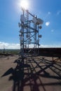 Telecommunication tower with microwave, radio antennas and satellite dishes with shadows on the roof Royalty Free Stock Photo