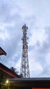 Telecommunication tower over the roof and cloudy blue sky background Royalty Free Stock Photo