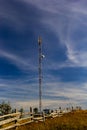 Telecommunication tower with radio, microwave and television antenna system located in the forest against the blue sky. Antenna Royalty Free Stock Photo