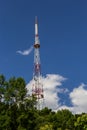 Telecommunication tower with radio, microwave and television antenna system located in the forest against the blue sky. Antenna Royalty Free Stock Photo