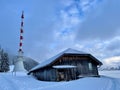 Telecommunication tower and wooden hut on mountain top in winter at sunset. Royalty Free Stock Photo