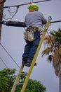 A telecommunications lineman works from a tall ladder to install new fiber optic cable and perform maintenance.