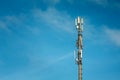 Telecommunications mast set against blue sky and big white cloud Royalty Free Stock Photo