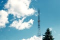 Telecommunications mast set against blue sky and big white cloud Royalty Free Stock Photo