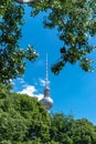 Telecommunications tower of berlin caressed by the leaves of some trees.