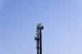 Telecommunications tower with cellular antennas and repeaters against a clear blue sky with two traces of flying aircraft Royalty Free Stock Photo