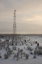 Telecommunications tower and satellite dish telecom network on evening sky with sundown and winter north forest Royalty Free Stock Photo