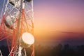 Telecommunications tower and satellite dish telecom network with silhouette of countryside area in sunrise Royalty Free Stock Photo