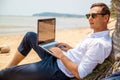 Telecommuting, businessman relaxing on the beach with laptop and palm, freelancer workplace, dream job. Royalty Free Stock Photo