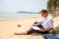 Telecommuting, businessman relaxing on the beach with laptop and palm, freelancer workplace, dream job. Royalty Free Stock Photo