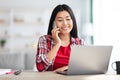 Telecommuting Concept. Young Korean Female Talking On Cellphone And Using Laptop Royalty Free Stock Photo
