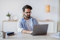 Telecommuting. Eastern Man Using Laptop Computer, Sitting At Desk In Home Office Royalty Free Stock Photo