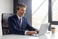 Telecommuting. Successful Middle Aged Manager Wearing Headset Working With Laptop In Office Royalty Free Stock Photo