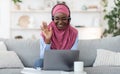 Teleconference. Smiling black muslim woman in headset making video call with laptop