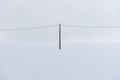 A telegraph pole standing alone on a completely snowy hill. Symmetrical composition, where the pole divides the frame in half. Royalty Free Stock Photo