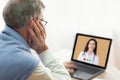 Telehealth concept. Senior man having online video call with doctor on laptop computer at home Royalty Free Stock Photo