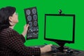 A telemedicine doctor looks at an x-ray in front of a green screen monitor. Royalty Free Stock Photo