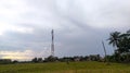 A telephone tower in a field with a house in the background Royalty Free Stock Photo