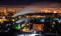 Telephoto lens long exposure shot of night cityscape with pipe and chimney emitting steam or smoke Royalty Free Stock Photo