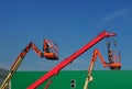 Telescopic crane and two aerial platforms of cherry pickers in a construction site