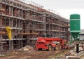 Telescopic handler between a building under construction covered with scaffolding and a concrete batching silo