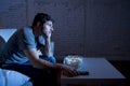 Television addict man sitting on sofa watching TV eating popcorn using remote control looking bored Royalty Free Stock Photo