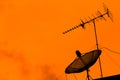 Television antenna and satellite dish on the roof with sunset sk