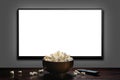 Television on a gray wall with remote control and popcorn bowl on the table. White blank HD monitor mockup. Royalty Free Stock Photo