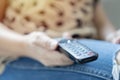 Television remote control in female hands pointing to tv set and turning it on or off Royalty Free Stock Photo