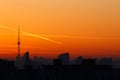 A television tower but against a background of bright orange sunset and the city. Traces of the plane in the sunset sky Royalty Free Stock Photo