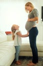 Tell the baby to come out to play now. a pregnant woman spending time with her little girl. Royalty Free Stock Photo