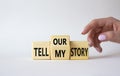 Tell our or my story symbol. Businessman hand points at wooden cubes with words Tell my story and tell our story. Beautiful white Royalty Free Stock Photo