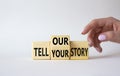 Tell Your or Our story symbol. Businessman hand points at wooden cubes with words Tell Our story and Tell Your story. Beautiful Royalty Free Stock Photo