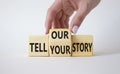 Tell Your or Our story symbol. Businessman hand turns wooden cubes and changes the words Tell your story to Tell our story. Royalty Free Stock Photo