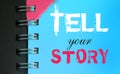 Tell your story words on sky blue page of copyybook in white and pink. Storytelling copywriting concept