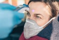 Temperature check point - the woman behind the wheel of the car in an anti-virus mask is subjected to temperature measurement Royalty Free Stock Photo