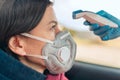 Temperature check point - the woman behind the wheel of the car in an anti-virus mask is subjected to temperature measurement