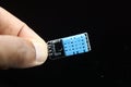 Temperature and humidity sensor module or DHT11 board held in hand isolated on black background Royalty Free Stock Photo