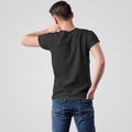 Template of male black t-shirt on a young guy in jeans, rear view, isolated on a white background