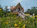 Temple in Pra That Bang Phuan temple in Nong Khai province of Thailand with yellow flowers foreground.