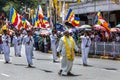 A Temple Priest strides ahead of a group of Buddhist Flag Bearers during the Day Perahera in Kandy in Sri Lanka.