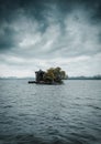 A temple in small island located in the middle of a river under heavy clouds. Dark blue Isolated island in a river