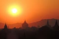 The temples of Bagan, Myanmar before sunset with mountains in the back and an organge and yellow sky Royalty Free Stock Photo