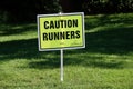 Temporary yellow parkrun sign in the UK advising 'Caution Runners'