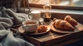 Breakfast of croissants and coffee on wooden tray on bed